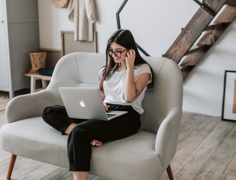 Chica Adolescente sentada en el sofá del salón de casa con un ordenador portatil laptop mientras estudia feliz porque está siguiendo uno de los tratamientos del TDAH con evidencia científica