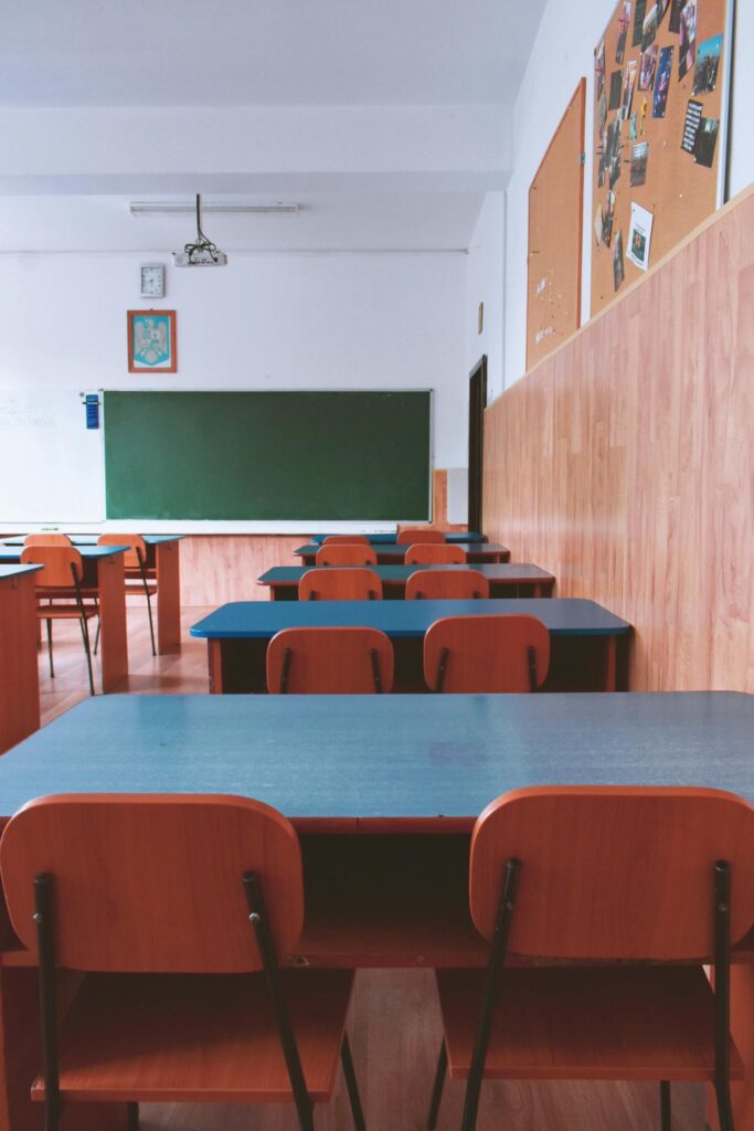 Aula de una clase de colegio con pizarra y pupitres vacíos